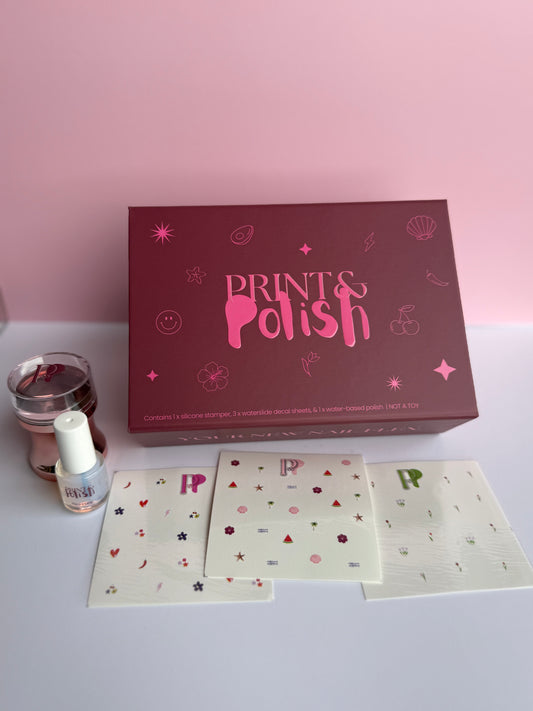 Prints & Polish nail art kit with box, cards, and nail polish on a light pink background