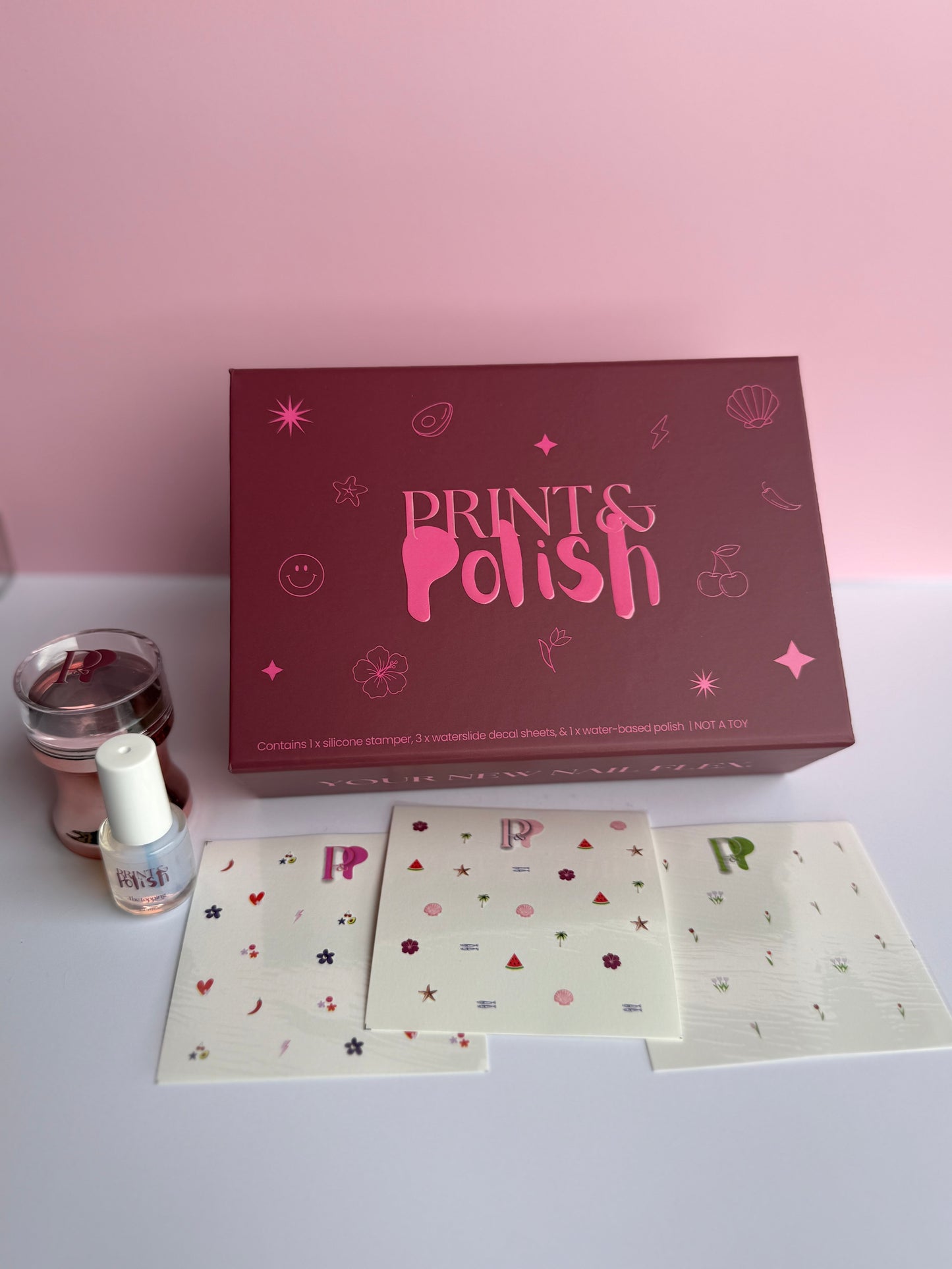 Prints & Polish nail art kit with box, cards, and nail polish on a light pink background