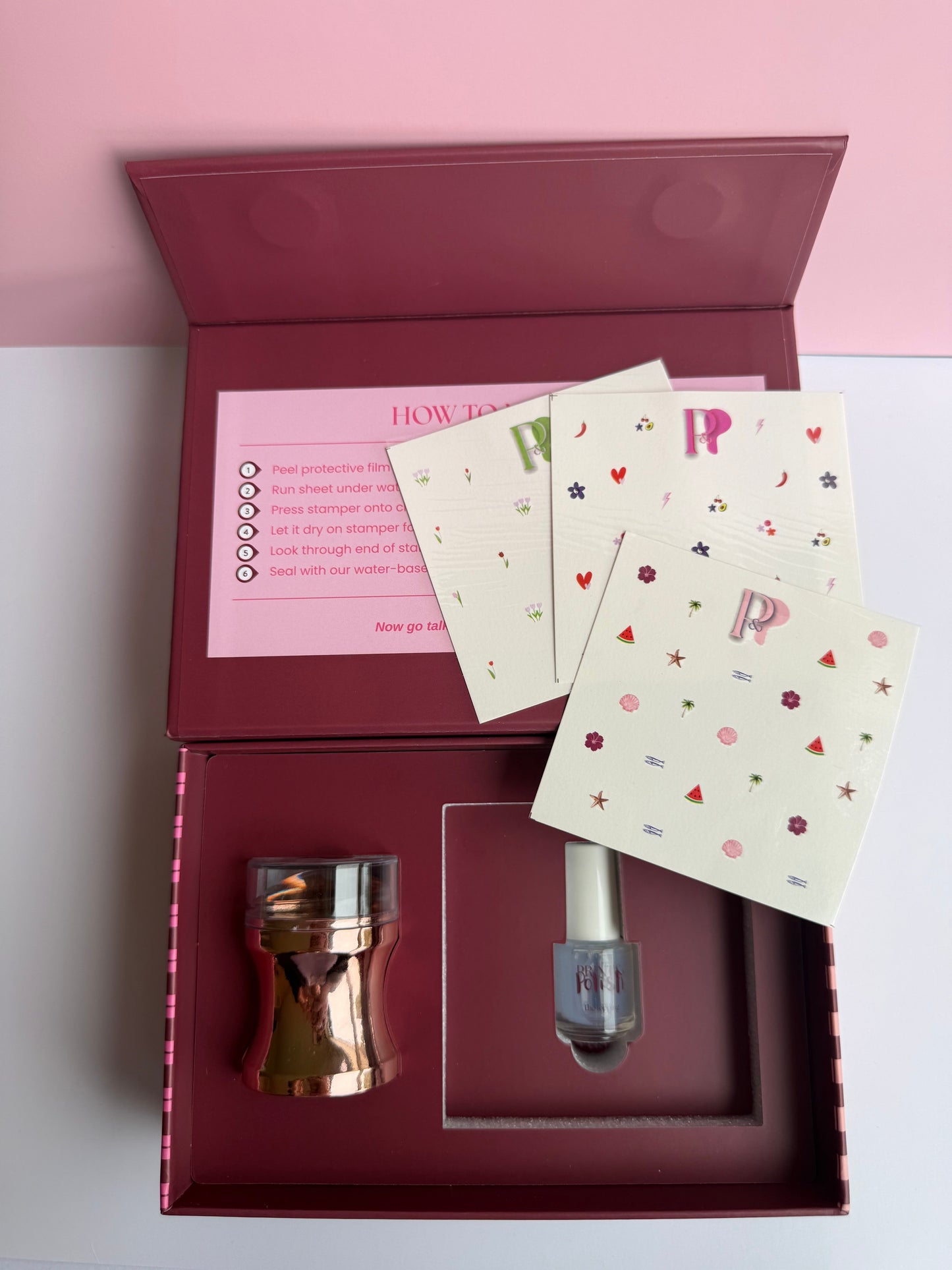 Nail art kit product with accessories and instructions in a box on a pink background