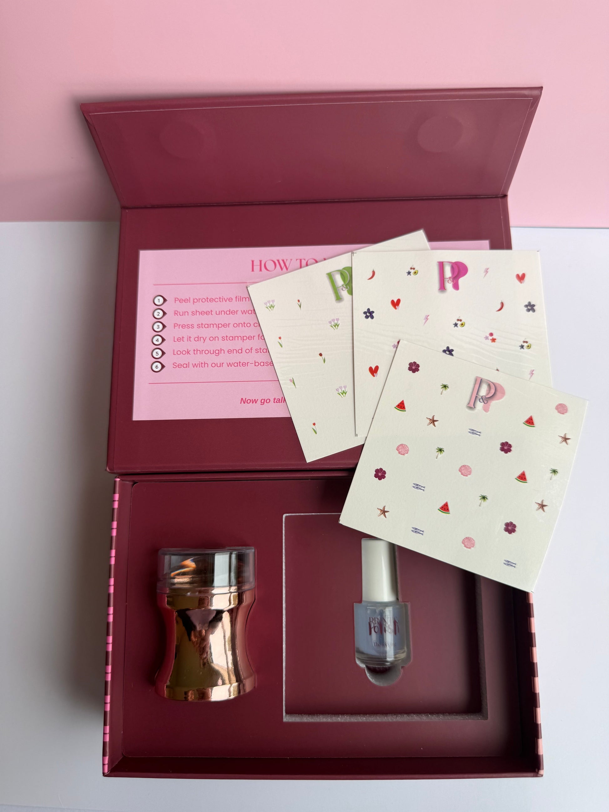 Nail art kit product with accessories and instructions in a box on a pink background